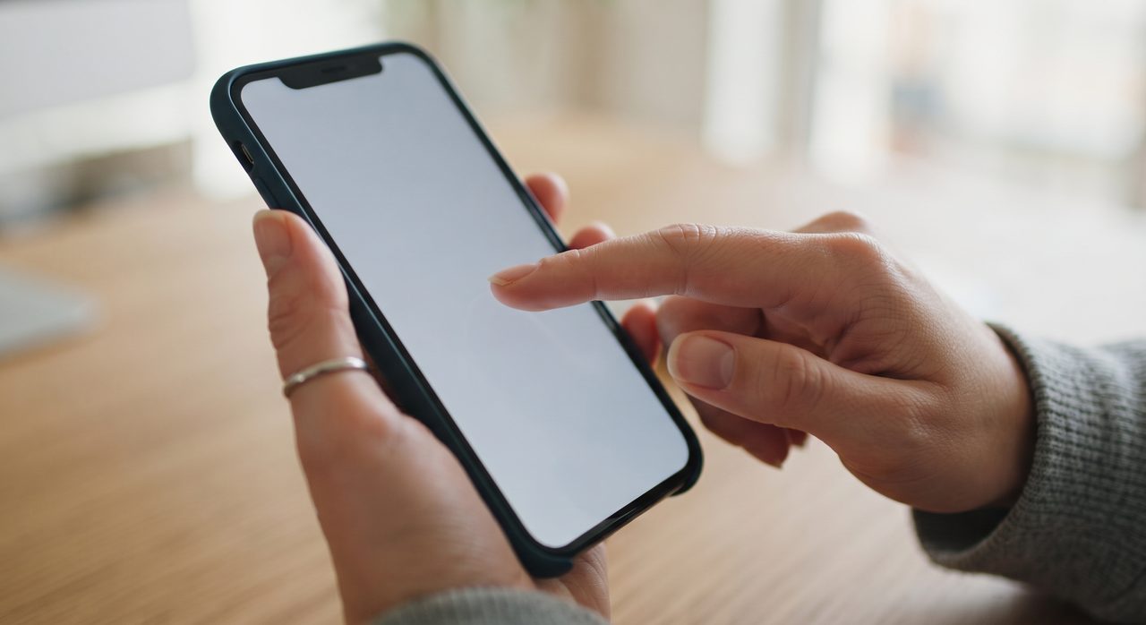 手元でスマートフォンの画面を指先で操作している様子のクローズアップ